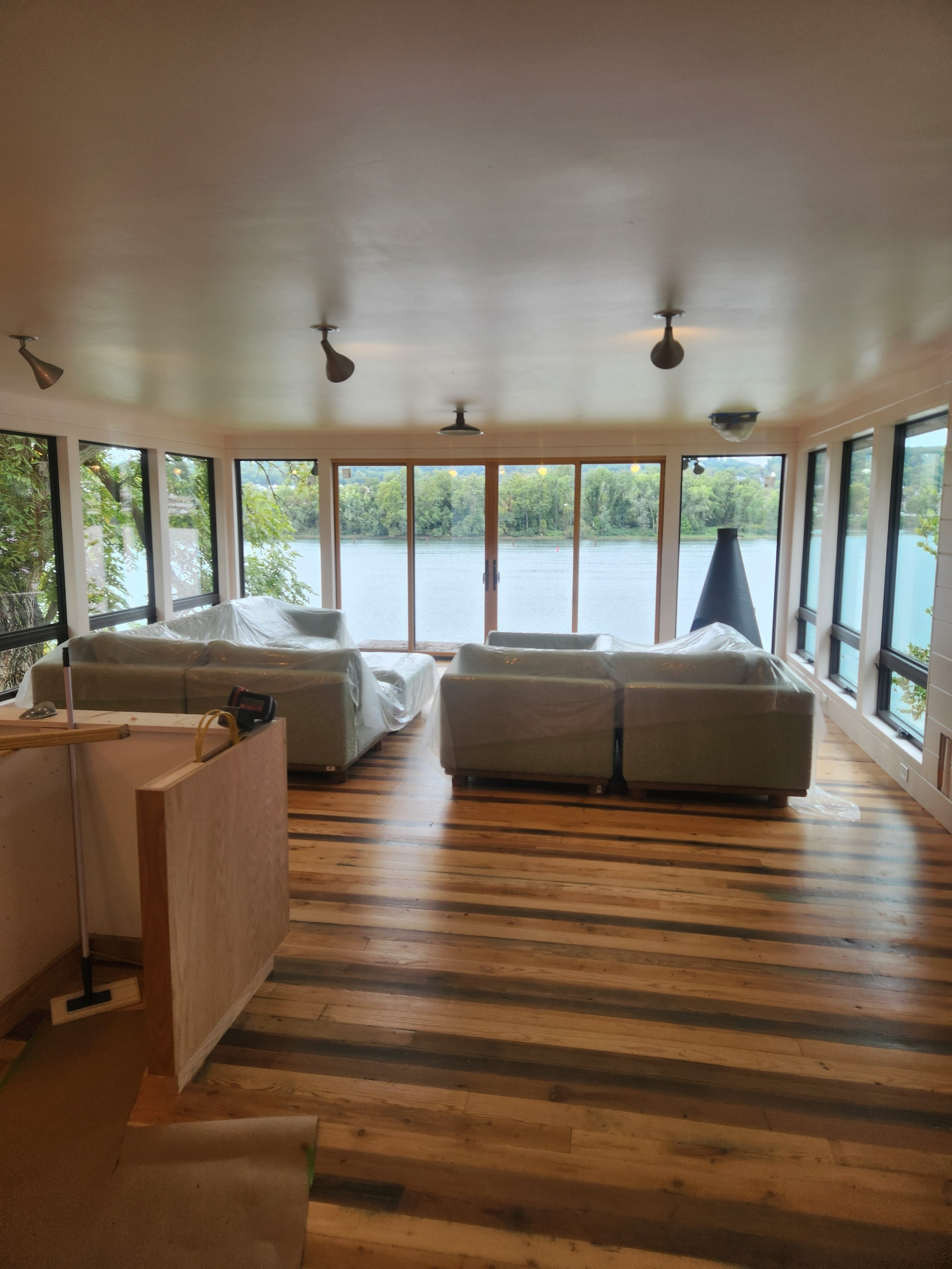Completed Josiah Construction lakefront room addition with panoramic windows and mixed hardwood floors