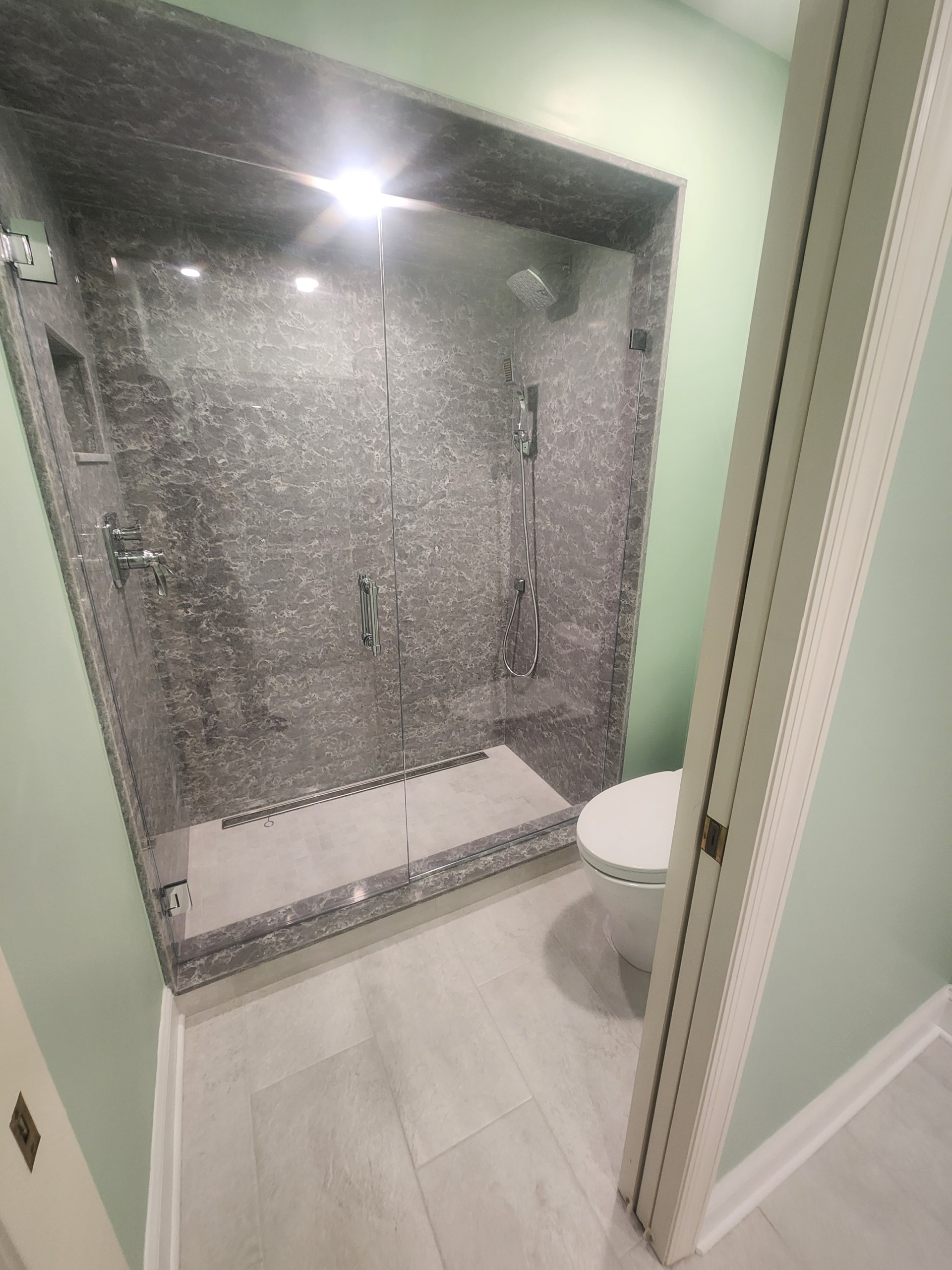 Dark marble shower with frameless glass enclosure